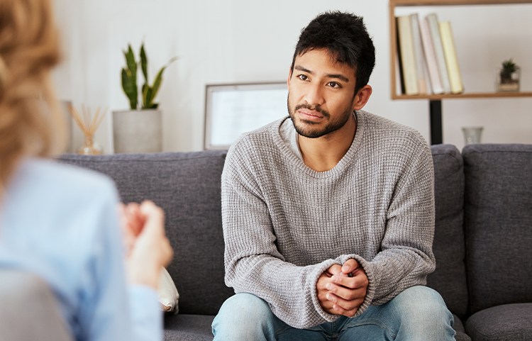 Person sitting across from another person on couch listening